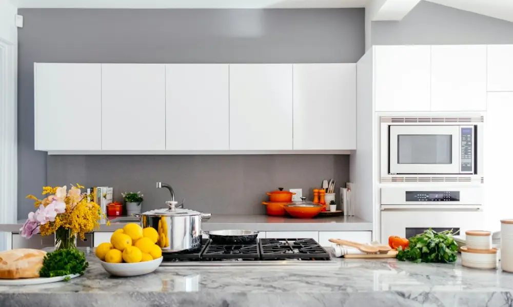 Modern white kitchen with marble island, illustrating planning ventilation around kitchen use